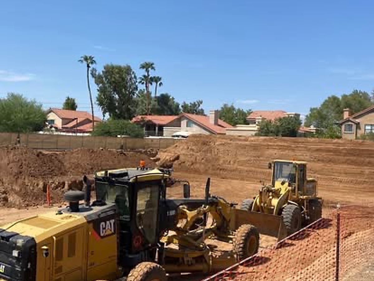 Motor grader working a lot next to an Arizona residential neighborhood