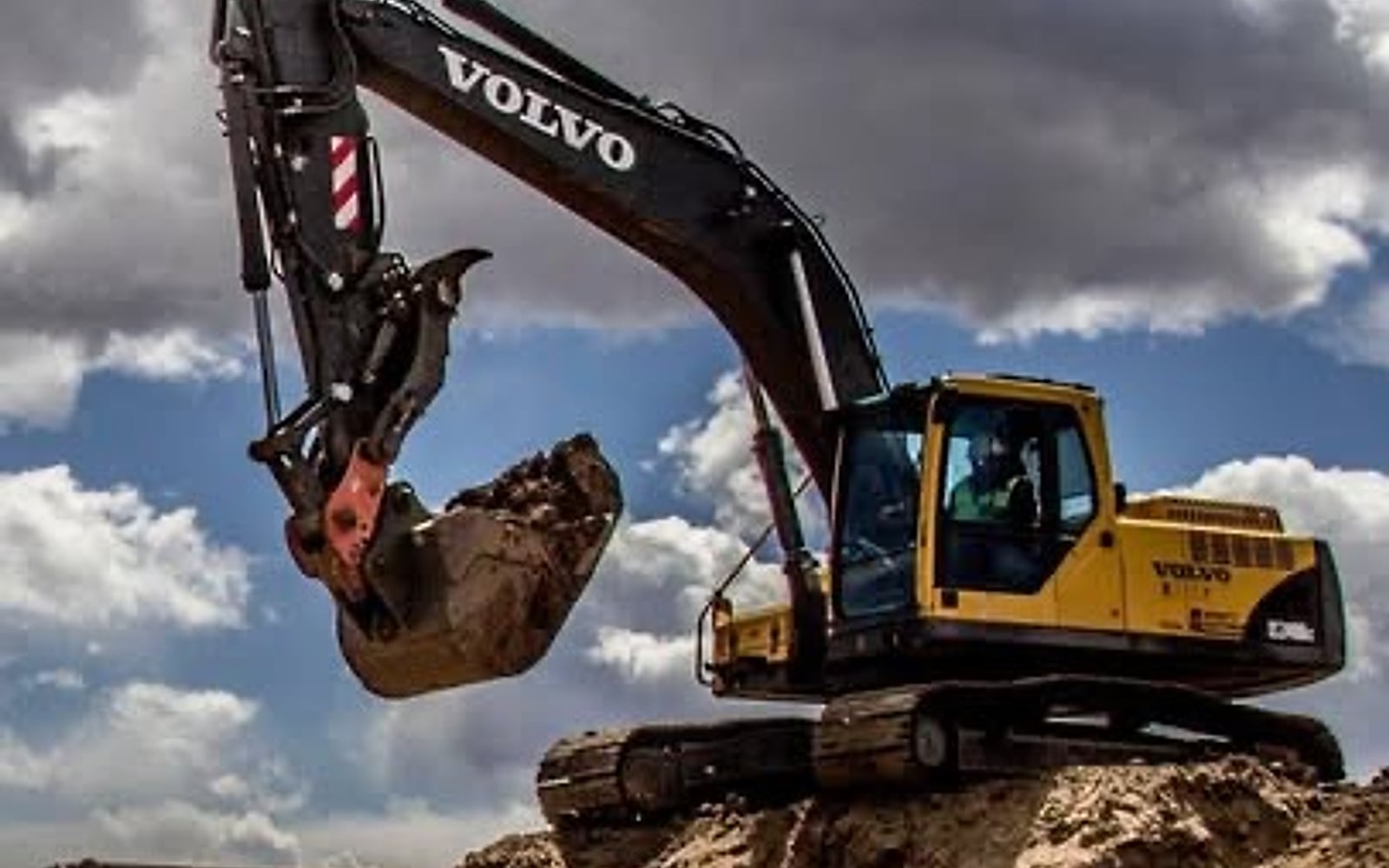 Volvo excavator digging on an Arizona jobsite under dramatic clouds