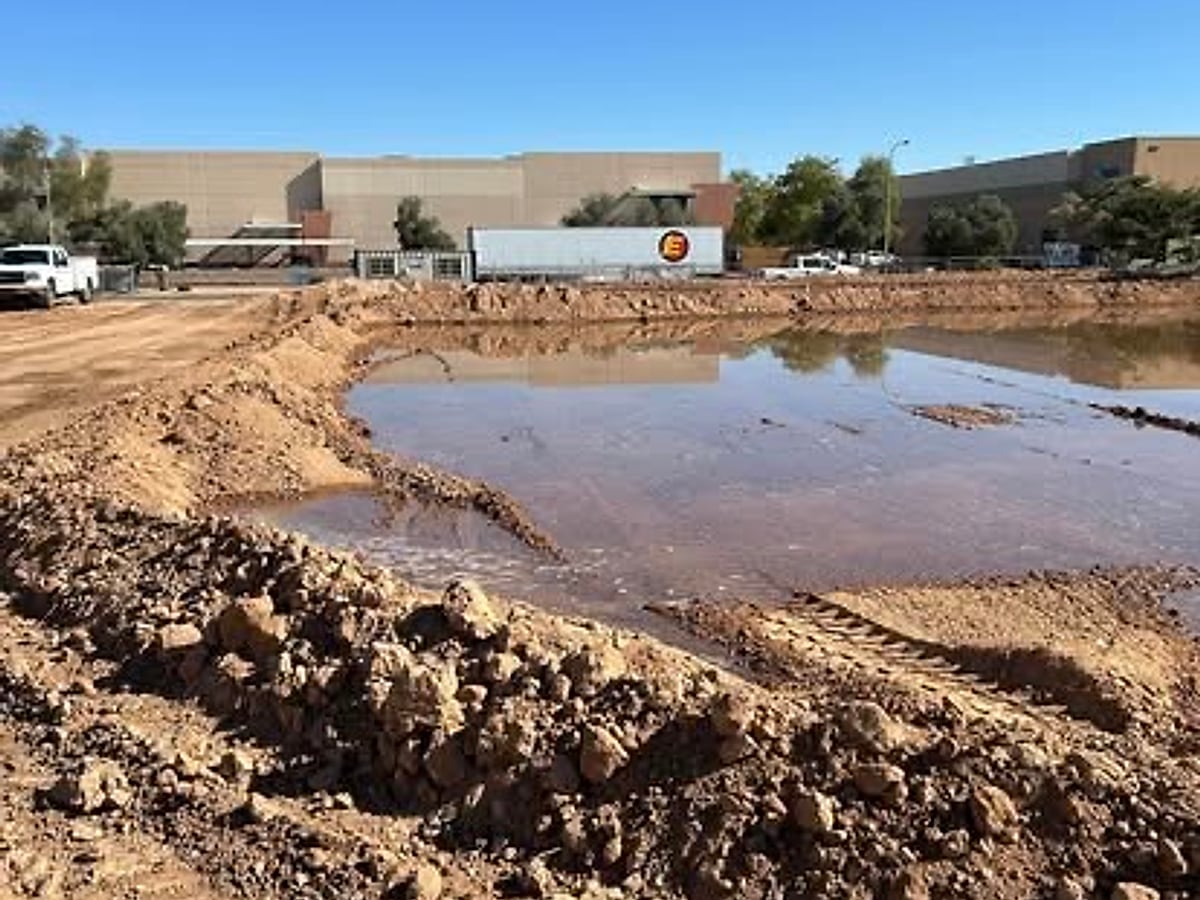 Excavated retention basin holding water near a commercial building