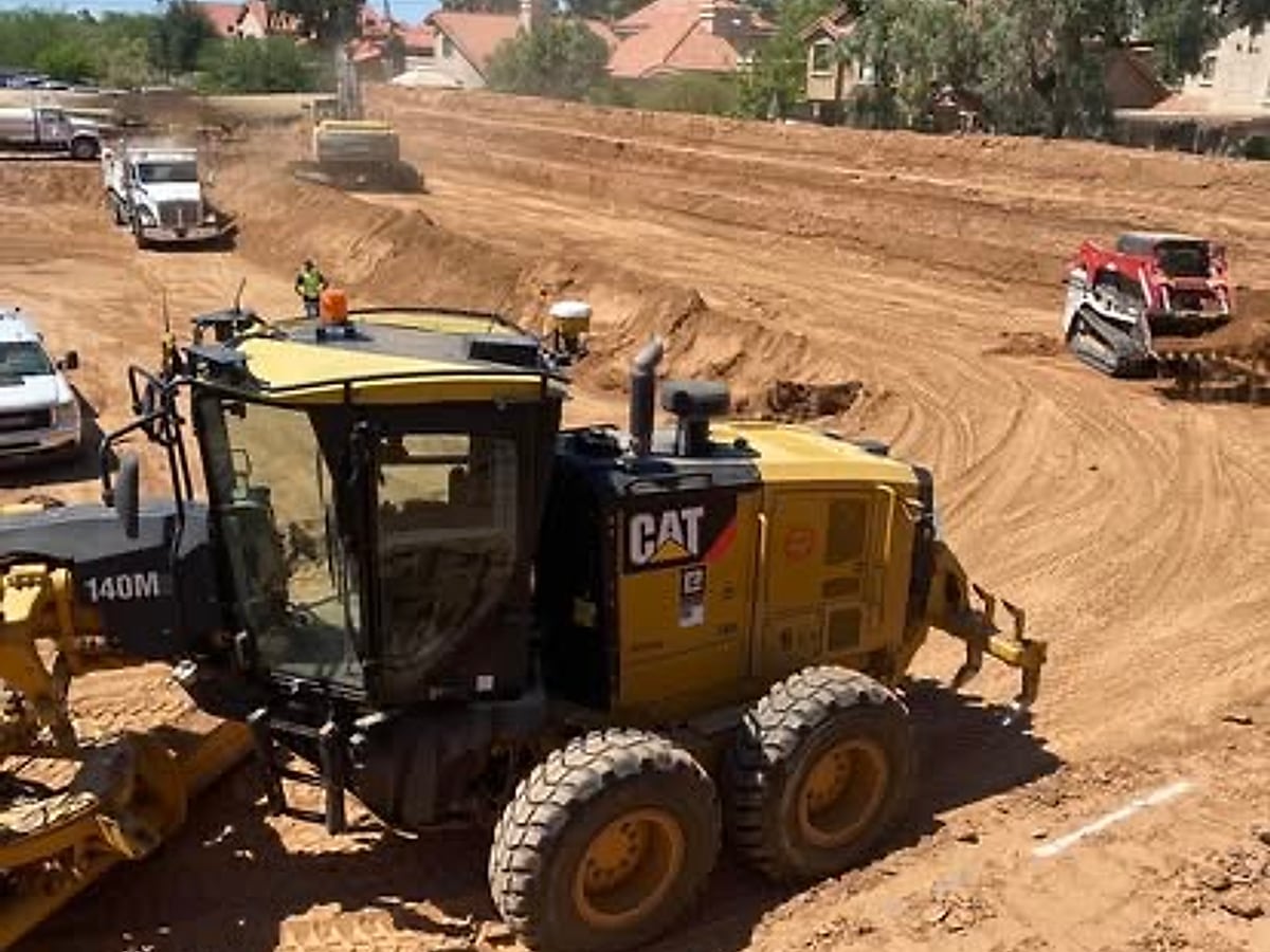 Caterpillar motor grader working a lot adjacent to an Arizona residential neighborhood
