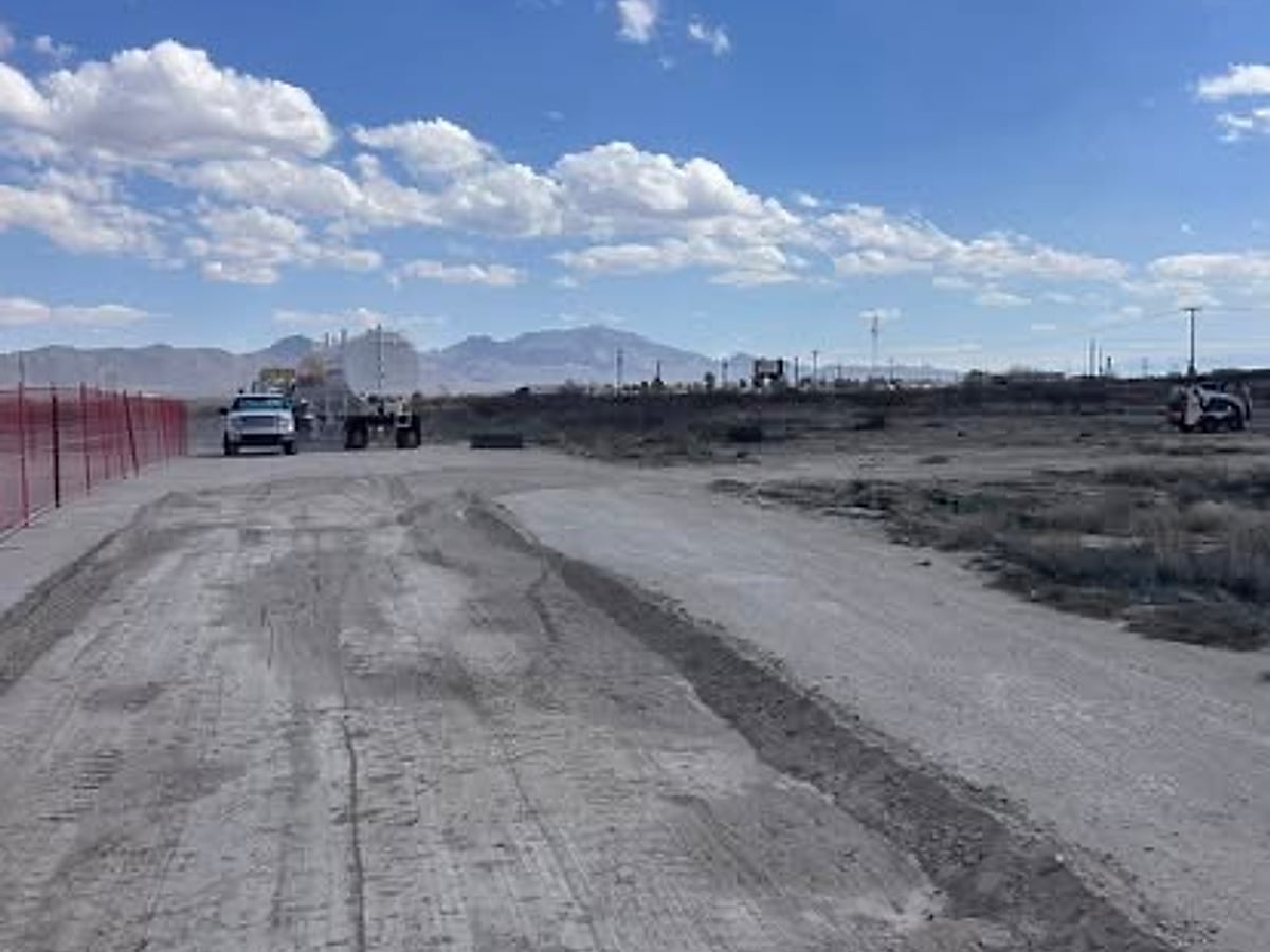 Excavator working a soil stockpile during site clearing with a haul truck nearby